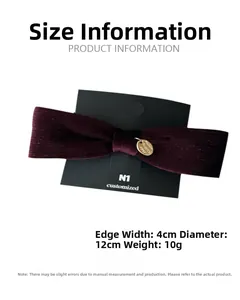 Close-up of burgundy velvet bow hair clip with gold metal tag on black display card