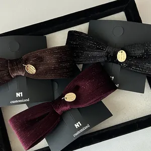 Detailed close-up of velvet bow hair clips in brown, black and wine red with gold charms