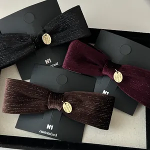 Detail of three velvet bow hair clips with gold charms in black, red and brown colors