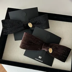 Detail of velvet bow hair clips with gold metal tags in black and dark brown