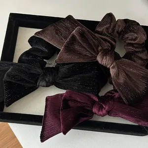 Detail of velvet bow hair scrunchies with metallic shimmer in black, brown and burgundy