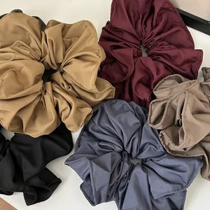 Flat lay of colorful matte fabric scrunchies in beige, burgundy, black and blue