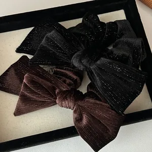 Detail of velvet bow hair ties with shimmering glitter texture in black and brown