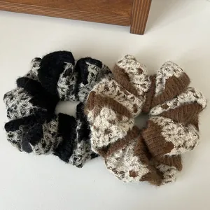 Detailed view of plush knitted scrunchies featuring retro plaid patterns in black and brown
