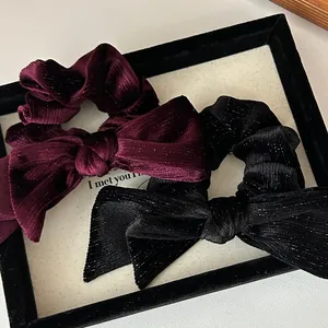 Macro shot of velvet scrunchies with bow details in burgundy and black glitter fabric