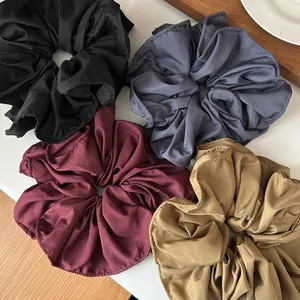 Detail of large ruffled scrunchies in black, gray, burgundy, and khaki matte fabric texture