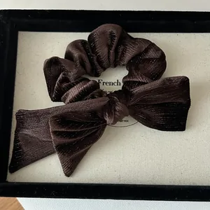 Macro shot of brown velvet scrunchie with long ribbon bow and subtle gold glitter