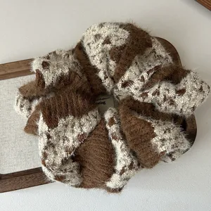 Detail of soft plush knitted hair scrunchie with brown and beige spotted pattern
