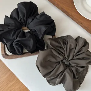 Detailed view of oversized ruffled hair scrunchies in classic black and deep brown fabrics