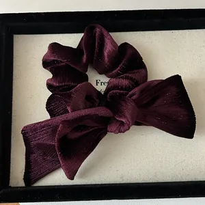 Detailed close-up of dark purple velvet bow scrunchie with subtle gold sparkle texture