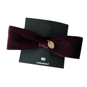 French vintage velvet bow hair clip with gold metal tag on black display card