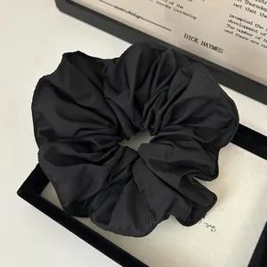 Detail view of a black ruffled scrunchie featuring elegant wavy edge stitching craftsmanship