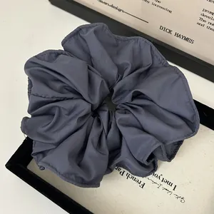 Close-up of charcoal grey ruffled scrunchie featuring high-quality matte fabric texture