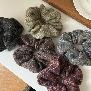 Detail of five colorful tweed knit scrunchies showing thick texture and retro patterns