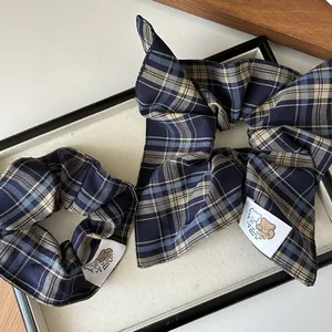 Detail of navy blue plaid scrunchie set with cartoon fabric label and retro bow design