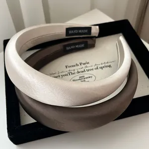 Padded satin headbands in champagne and brown colors with hand made labels in a wooden box