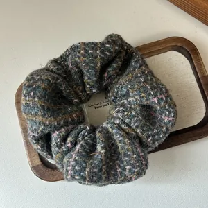 Close-up of retro tweed fabric texture on a thick knitted hair scrunchie in autumn colors