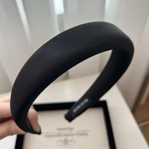 Macro detail of black satin padded headband showing smooth fabric texture and inner label