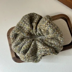 Macro view showing the rich texture of the green and brown tweed fabric scrunchie