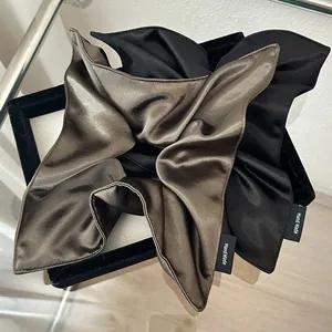 Close-up of silk satin scrunchies with Hand Made label in bronze and black tones