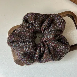 Detailed texture of thick multicolor tweed knit scrunchie on a rustic wooden tray