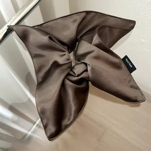 Detailed view of large coffee brown satin scrunchie with handmade woven label