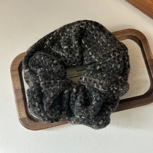 Detailed view of the multicolor tweed knit scrunchie with thick woven texture and plaid pattern