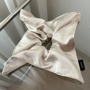Detailed macro view of handmade champagne satin silk scrunchie with gloss texture