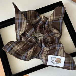Detail of a brown plaid scrunchie featuring a cartoon bear label and bunny ear design