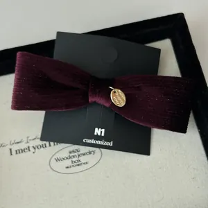 French retro burgundy velvet bow hair clip with vintage gold oval metal emblem