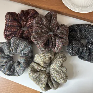 Five assorted retro tweed checkered large hair scrunchies displayed on a wooden tray