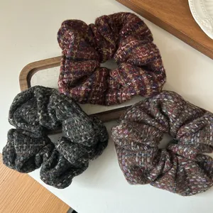 Colorful tweed knit scrunchies in red, green and purple on a rustic wooden tray