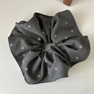 Détail d'un grand chouchou gris foncé avec motif floral pailleté argenté et texture sergé