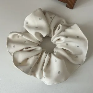 Gros plan d'un chouchou plissé beige avec des points pailletés argentés et tissu côtelé