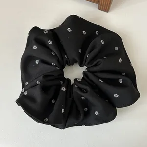 Gros plan détaillé d'un chouchou noir avec des paillettes argentées sur tissu