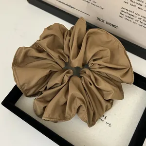 Elegant khaki fabric scrunchie with matte satin texture and ruffled edges for hair styling