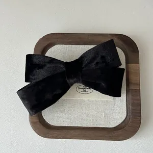 Dettaglio di un fermaglio per capelli con fiocco in velluto nero su vassoio in legno