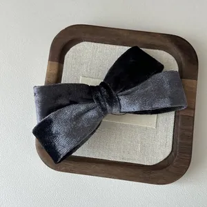 Dettaglio del fermaglio per capelli con fiocco in velluto bicolore nero e grigio elegante
