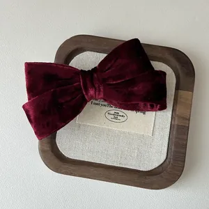 Dettaglio di un fermaglio a fiocco in velluto bordeaux con trama di lusso su vassoio