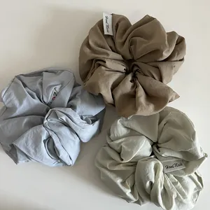 Trois chouchous en tissu bleu, marron et crème avec des étiquettes fait main