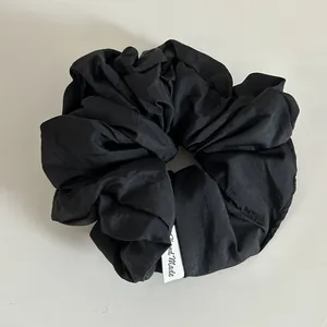 Gros plan du chouchou noir en tissu texturé avec étiquette tissée Hand Made