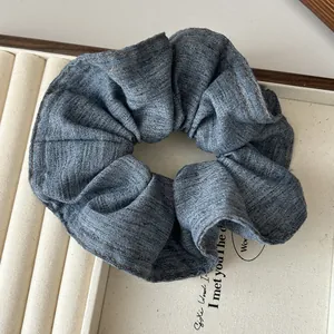 Gros plan du chouchou en denim bleu avec coutures contrastées sur plateau beige