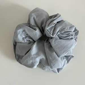Vue détaillée du chouchou gris clair oversize avec texture de tissu et petite étiquette interne