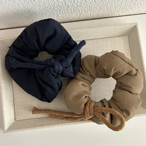 Navy and olive oversized puffy scrunchies with knotted cord detail in a textured tray
