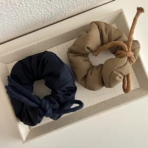Detail of padded cloth scrunchies in navy and olive with cotton rope knot decor