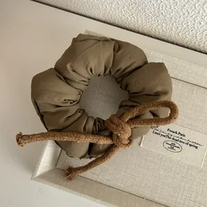 Detail of dark khaki padded scrunchie with rope bow knot in a cream gift box