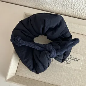 Detailed macro shot of the dark fabric scrunchie with a woven cotton rope tie