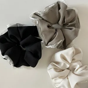 Detail of 3 mesh lace hair scrunchies with pearls in black, grey and cream white