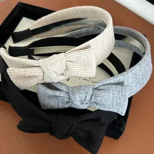 Dettaglio di tre cerchietti con fiocco in maglia in beige, grigio e nero su legno