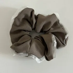 Detailed texture of brown fabric scrunchie with white lace trim and pearls